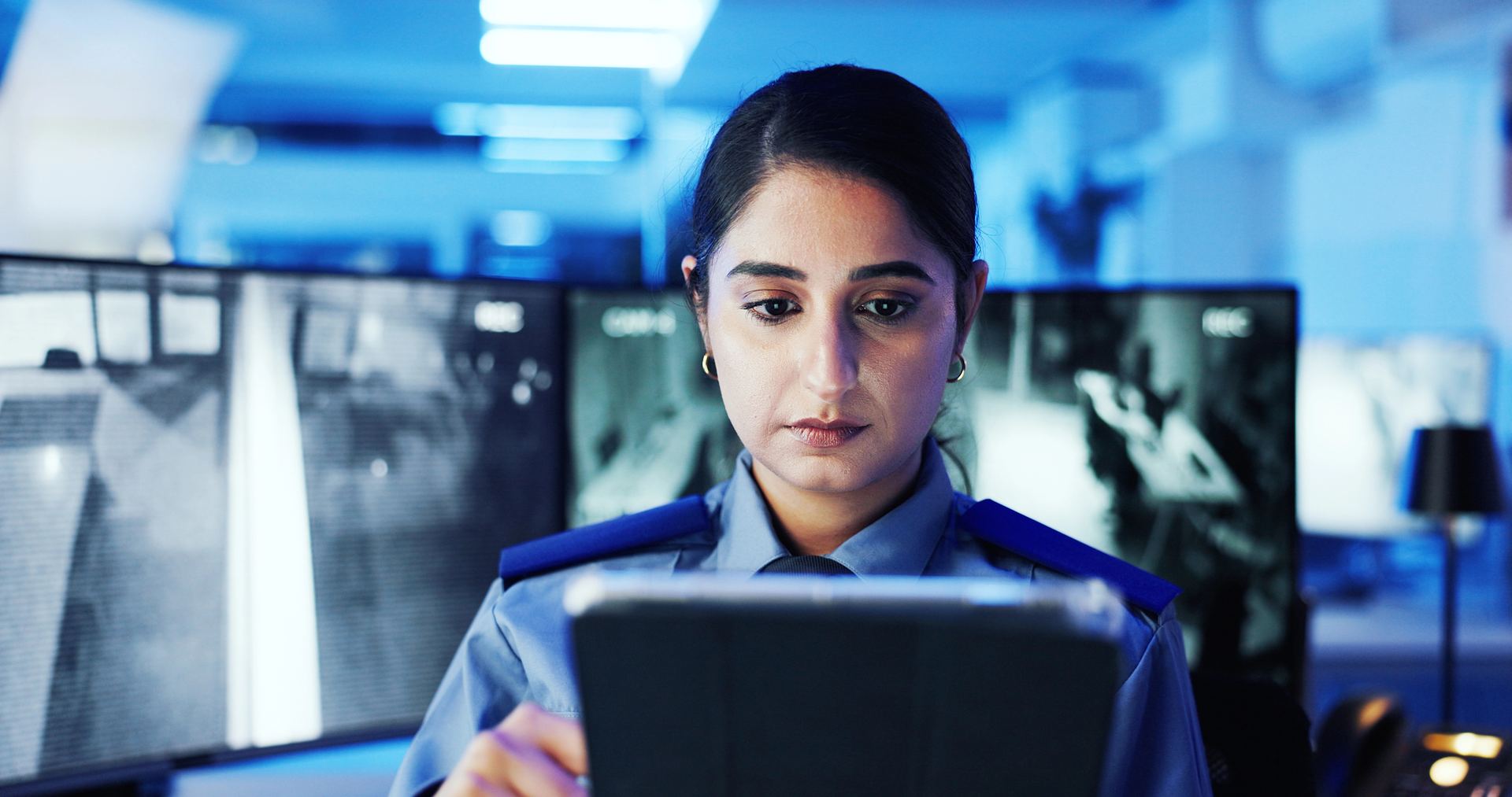 Security operative reviewing information on a tablet in a monitoring control room